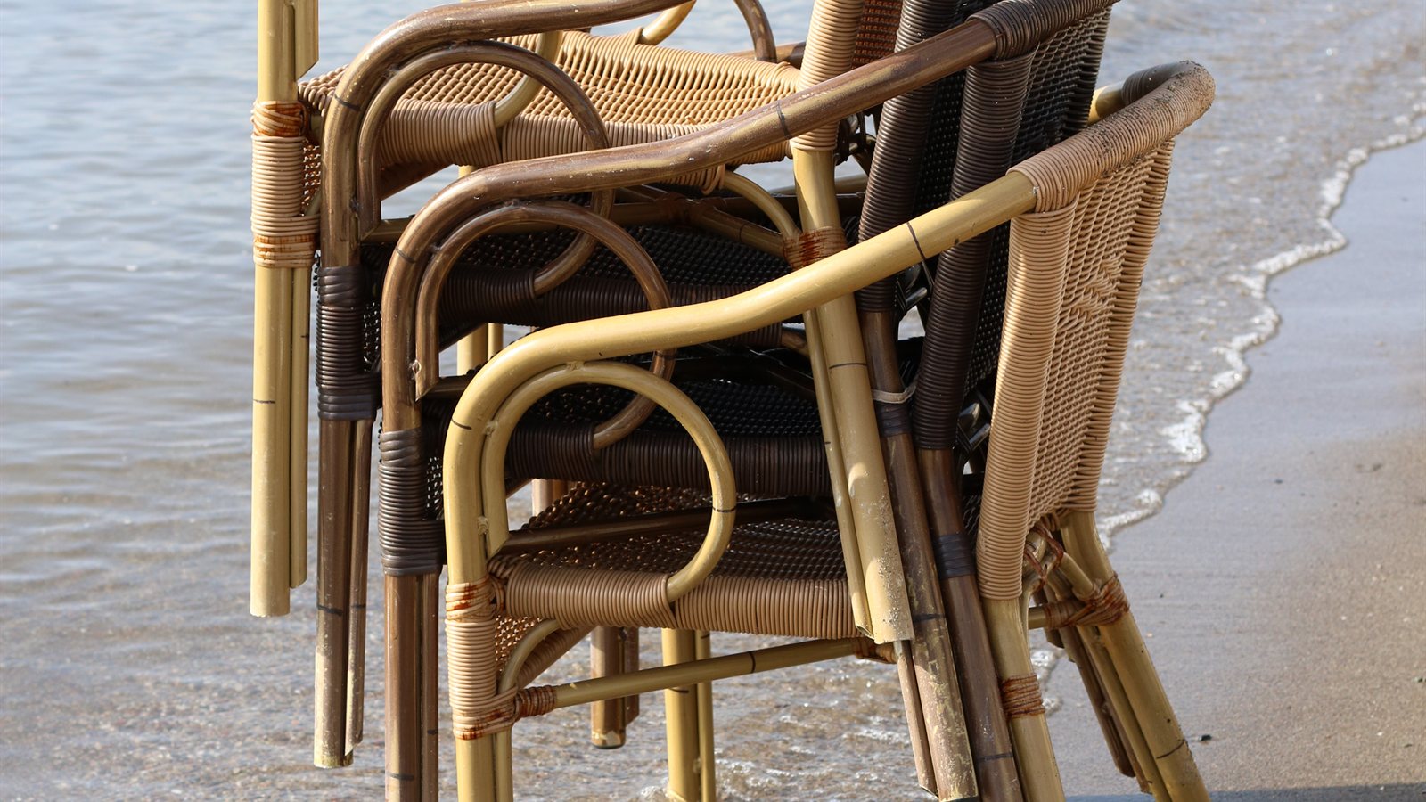 Stacked wicker chairs standing in shallow water at the shoreline